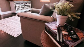 A living room with a brown leather sofa, a round wooden coffee table, a potted plant, a remote control, and a book titled 'Living Misadventures.' - Wolf River Ridge on DHL 
1 minute from boat ramp! 
Kayaks & Bikes included (Byrdstown)