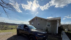 A black SUV parked in front of a house with a gravel driveway and a clear sky. - Wolf River Ridge on DHL 
1 minute from boat ramp! 
Kayaks & Bikes included (Byrdstown)