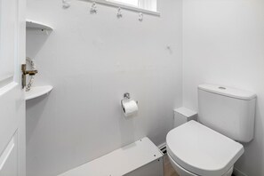 A small, white bathroom with a toilet, a sink, and a shower area. - Refurbished 4BDR Home in Harborne Birmingham (Birmingham)