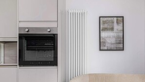 Uma cozinha com forno embutido, radiador e um quadro na parede.