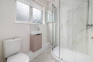 Ein Badezimmer mit Toilette, Waschbecken, Waschtisch und einer Duschkabine.