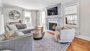 Un salon moderne avec une cheminée, un grand téléviseur et un coin salon confortable.