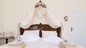 Un letto rifatto con lenzuola bianche, una testiera in legno e un baldacchino.