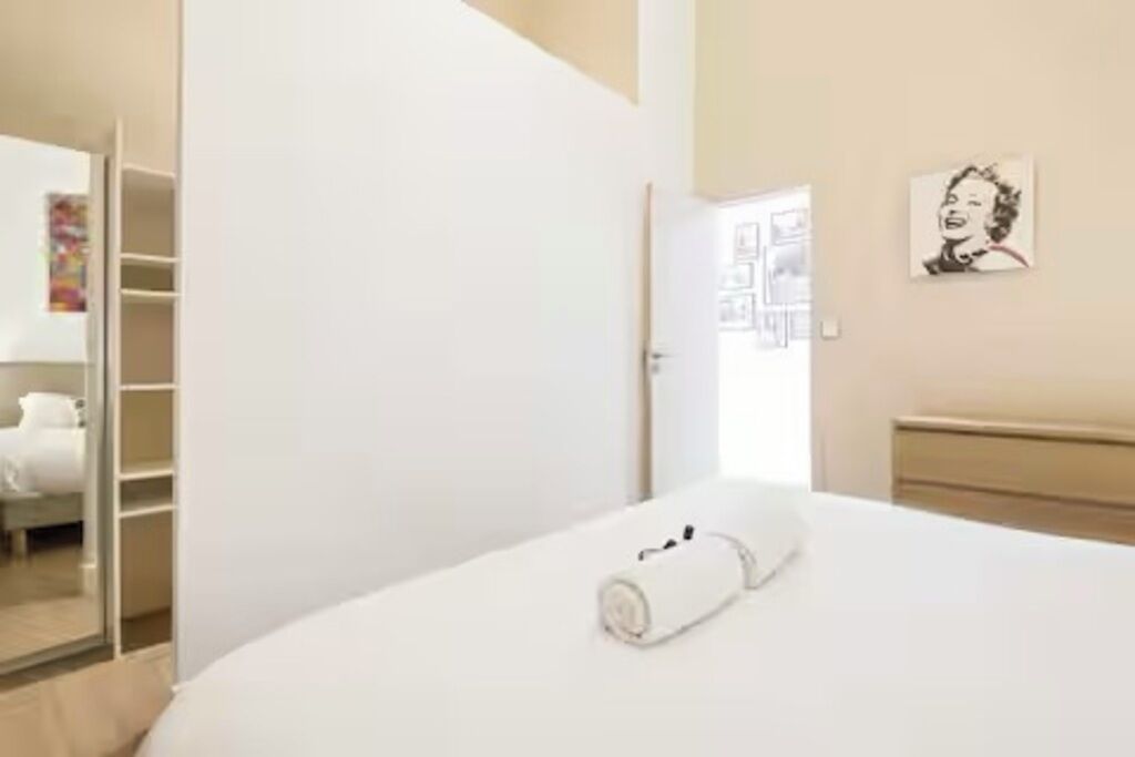 Une chambre à coucher avec un lit, une armoire et un mur orné d’un tableau.