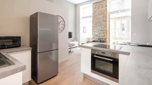 A modern kitchen with a refrigerator, microwave, oven, and a large window providing natural light.
