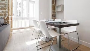 A modern dining area with a white table and chairs, a stone wall, and a view of a balcony.