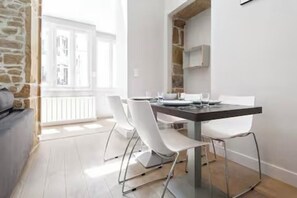 Un comedor moderno con una mesa y sillas blancas, una pared de piedra y vistas a un balcón.
