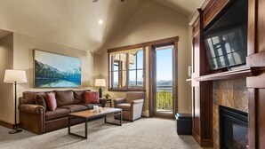 A living room with a fireplace, a sofa, a coffee table, and a painting on the wall. - Lux Slope-side 1BR.2BAw/FullKitchen, 1 King, 1 Queen Sofa  @ Grand Lodge Peak 7 (Breckenridge)
