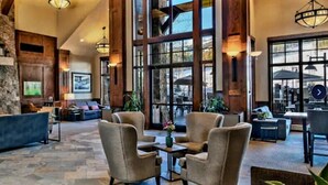 A spacious lobby with a stone fireplace, comfortable seating, and large windows offering views. - Lux Slope-side 1BR.2BAw/FullKitchen, 1 King, 1 Queen Sofa  @ Grand Lodge Peak 7 (Breckenridge)