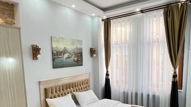 A bedroom with a large bed, a nightstand, a wooden floor, and a painting on the wall. - Mar Suite (İstanbul)
