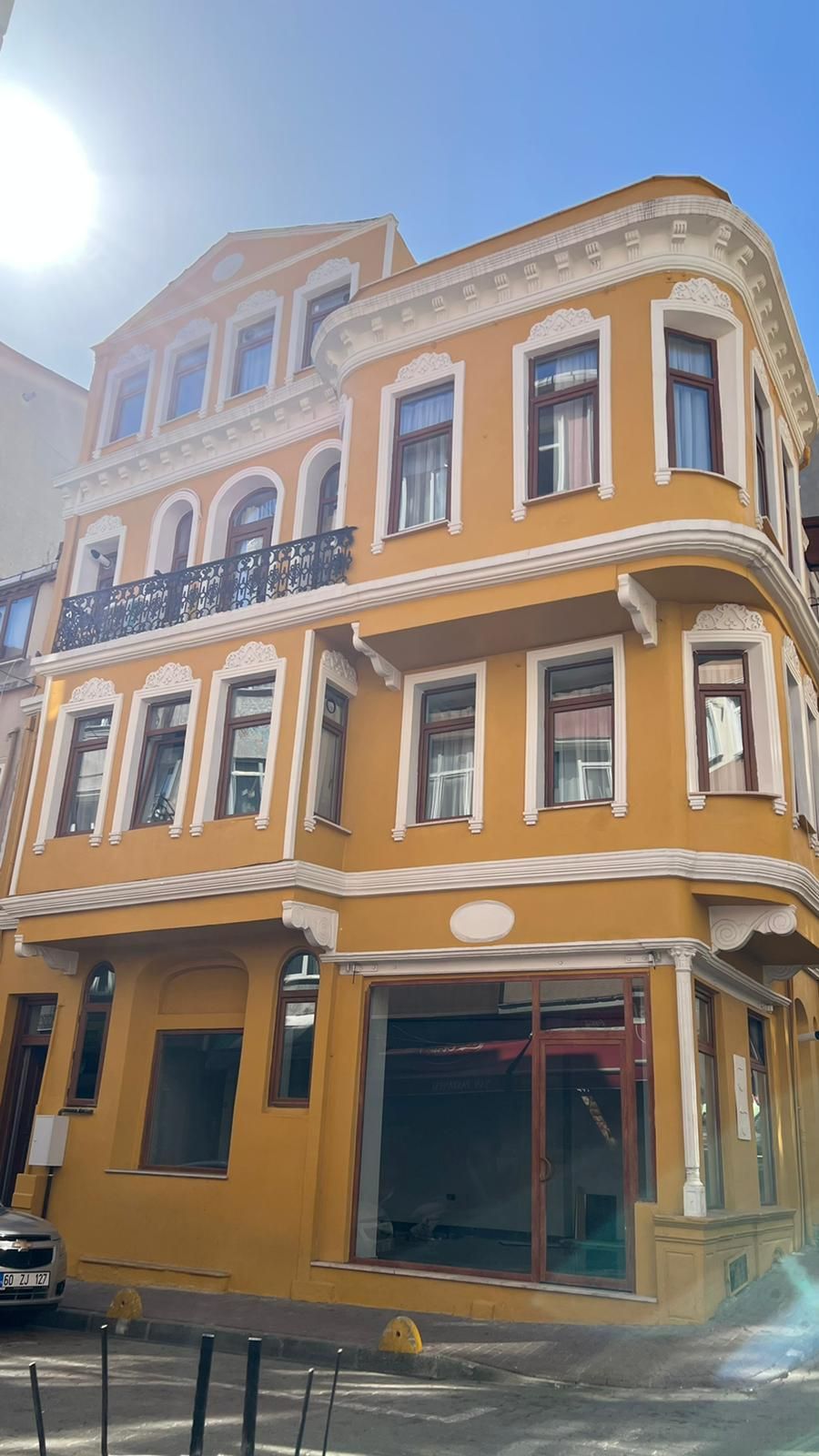 A multi-story building with a yellow facade, large windows, and a balcony.