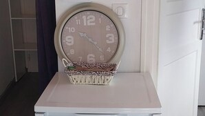 Un electrodoméstico blanco con un reloj en la parte superior, una cesta y una puerta con manija.