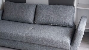 Un sofá gris con respaldo que presenta un estampado de cuadros en tonos oscuros y claros.