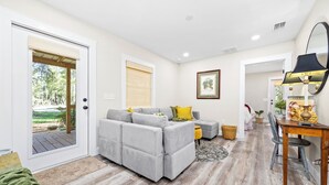A modern living room with a grey sectional sofa, a dining table with chairs, and a large mirror. - New Cottage within minutes from our Famous Springs! (Fort White)