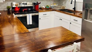A modern kitchen with white cabinets, stainless steel appliances, and a wooden island. - New Cottage within minutes from our Famous Springs! (Fort White)