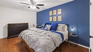 Quarto com cama, cômoda e ventilador de teto.