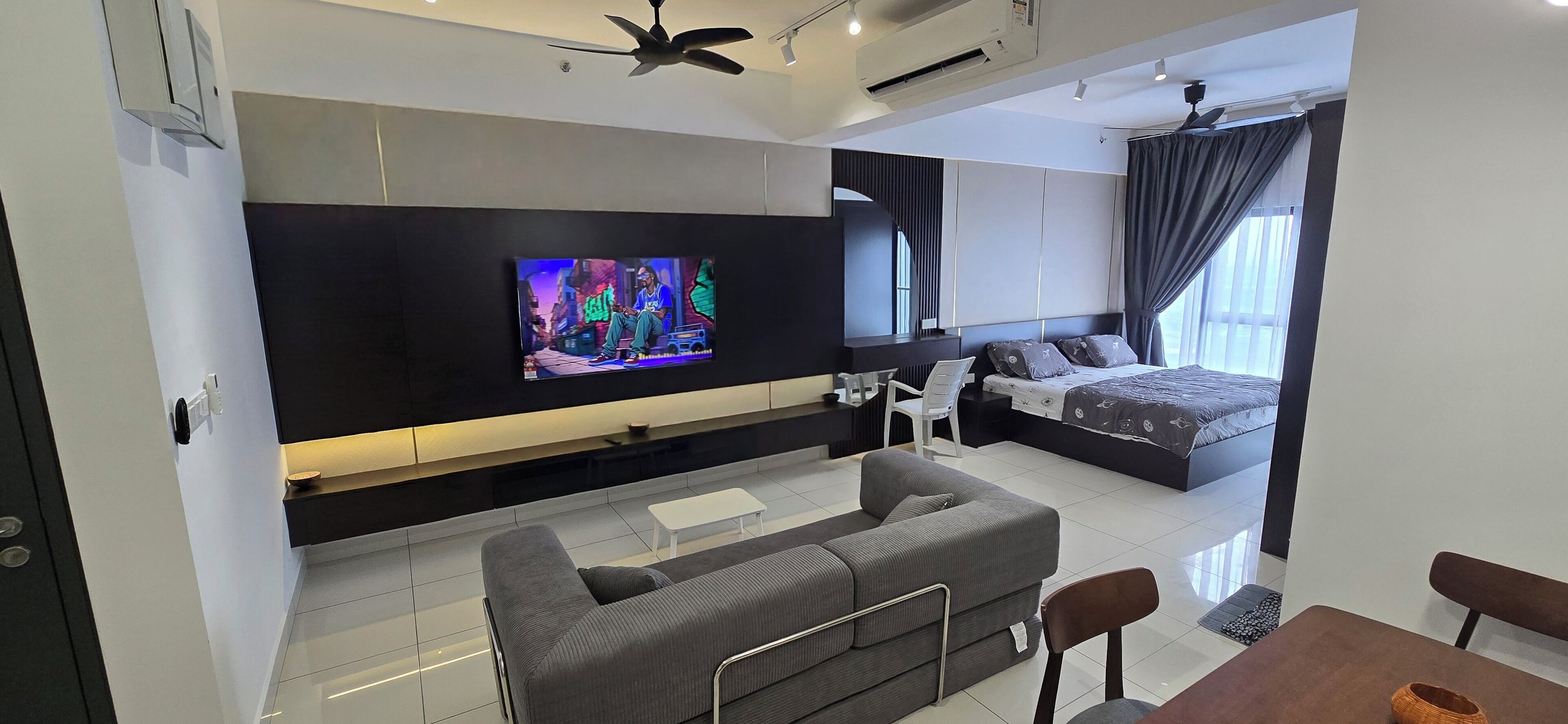 Une chambre moderne avec un grand lit, un téléviseur fixé au mur, un canapé et une table à manger.