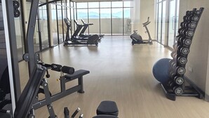 A gym with exercise equipment, a bench, and a rack of dumbbells.