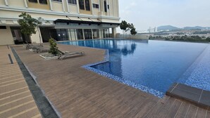A rooftop infinity pool with a view of a cityscape and mountains in the background.