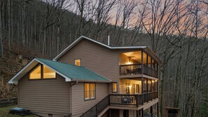 Een chalet met twee verdiepingen en een balkon, omgeven door bos.