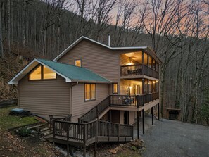 Eine zweistöckige Holzhütte mit einem Balkon, umgeben von einem Wald.