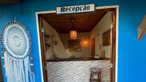 Un'area reception con una parete in pietra, un bancone in legno e un cartello con la scritta 'Recepção'.