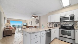 A modern kitchen with white cabinets, stainless steel appliances, and a large island. - New! Beachfront 2BR, Stunning Gulf Views, Indoor/Outdoor Pools, Hot Tubs (Gulf Shores)