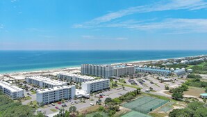 A coastal hotel complex with multiple buildings, parking areas, and a beach view. - New! Beachfront 2BR, Stunning Gulf Views, Indoor/Outdoor Pools, Hot Tubs (Gulf Shores)