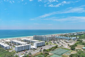 A coastal hotel complex with multiple buildings, parking areas, and a beach view. - New! Beachfront 2BR, Stunning Gulf Views, Indoor/Outdoor Pools, Hot Tubs (Gulf Shores)