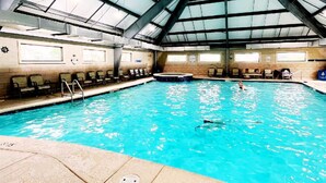 An indoor swimming pool with clear water, a high ceiling, and multiple viewing windows. - New! Beachfront 2BR, Stunning Gulf Views, Indoor/Outdoor Pools, Hot Tubs (Gulf Shores)