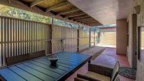 Eine Terrasse im Freien mit einem Holztisch und Korbstühlen.