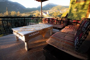 A balcony with a table and a sofa, overlooking a mountainous landscape. - VİTA CAMPING (Konyaalti)