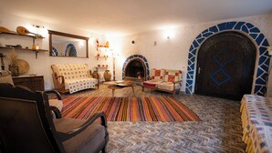 A cozy living room with a fireplace, a patterned rug, and a herringbone floor.