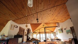 A room with a wooden ceiling, a kitchen area with a stove, and a dining area with a table and chairs.