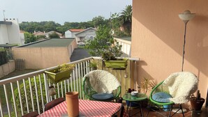 A balcony with a red and white checkered tablecloth, two chairs, and potted plants. - Large apartment in a quiet area, 2 terraces. (Biarritz)