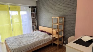 A bedroom with a wooden bed, a desk, a bookshelf, and a brick-patterned wall. - Large apartment in a quiet area, 2 terraces. (Biarritz)