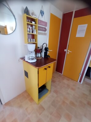 Eine kleine Küche mit einem gelben Schrank, einer Kaffeemaschine und einem Wasserkocher.