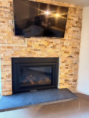 A fireplace with a TV mounted above it, set against a brick wall. - Walk to Slopes. 1BR/2BA Vail Condo. Sleeps 4.  Pool, Hot Tubs, Shuttle (Vail)