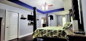 A bedroom with a bed, a ceiling fan, a TV, and a door. - Coastal Comforts Villa: Spacious 5BR Home Minutes from Navarre Beach (Gulf Breeze)