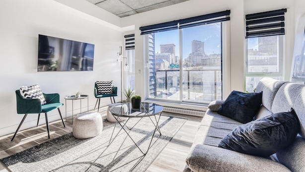 Uma sala de estar moderna com sofá, cadeiras, mesa de centro e uma janela grande com persianas.