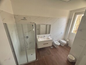 A modern bathroom with a glass-enclosed shower, a white sink, a bidet, and a large mirror above the sink. - Quiet apartment in serviced area 10 minutes' drive from Milan. (Bettola-Zeloforamagno)