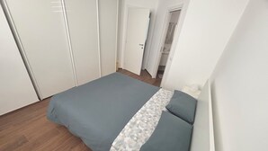 Ein Schlafzimmer mit Bett, Kleiderschrank und einer Tür zum Badezimmer.