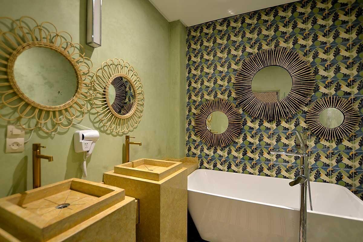 Ein Badezimmer mit einer freistehenden Badewanne, zwei Waschbecken mit Holztresen und drei wandmontierten Spiegeln mit runden Rahmen.