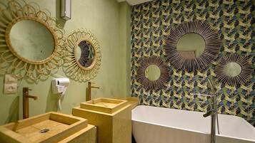 Ein Badezimmer mit einer freistehenden Badewanne, zwei Waschbecken mit Holztresen und drei wandmontierten Spiegeln mit runden Rahmen.