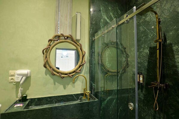 A bathroom with a glass-enclosed shower, a marble sink, a hairdryer, and a mirror with a rope frame. - Riad dar darcom (Marrakech)