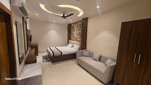 A bedroom with a bed, a sofa, a wardrobe, and a ceiling fan. - The Monark Inn (Sandila)