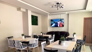 Un espace repas moderne doté d’un grand écran de télévision, de plusieurs tables et de chaises.