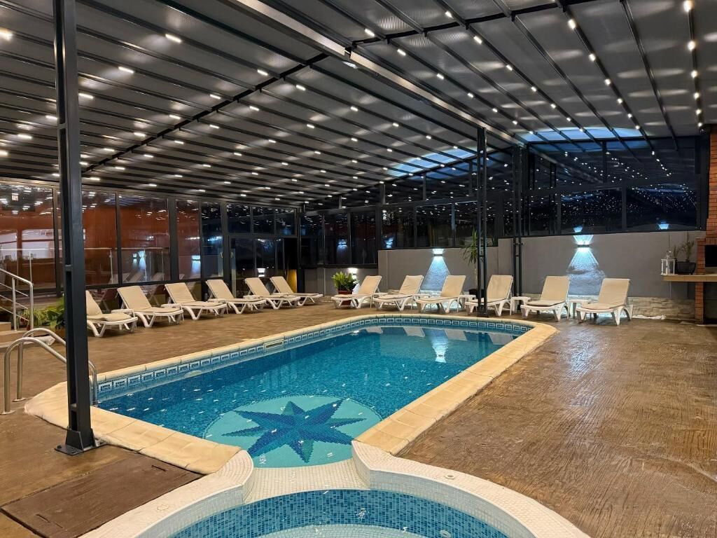 En indendørs swimmingpool med liggestole og et stjerneformet flisemønster.