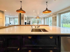 A spacious kitchen with a large island, pendant lights, and a view of the outdoors.