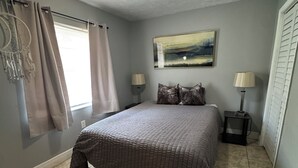 Un dormitorio con cama, dos lámparas de noche, una mesita de noche, un atrapasueños y un cuadro en la pared.